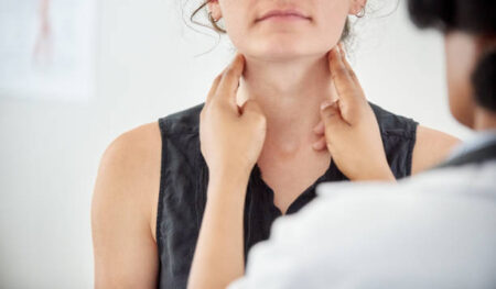 Close-up of a female doctor checking thyroid of a young woman patient in clinic