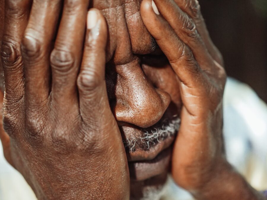 man with his hands covering his eyes, looking concerned